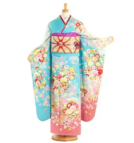 マネキンに着せられた日本の伝統的な着物。青、ピンク、クリーム色の鮮やかな花柄が描かれています。帯は金色に赤のアクセントが入り、長袖は優雅にドレープしています。.