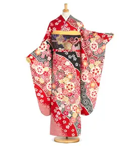 鮮やかな赤い着物に、ピンク、白、黒の色合いで複雑な花柄が描かれ、装飾的なモチーフがあしらわれた帯を締めたマネキン。無地の白い背景に立っている。.