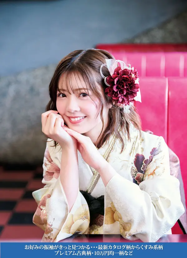 花柄の着物を着て、大きな花の髪飾りをつけた若い女性が赤いベンチに座り、左手にあごを乗せて微笑んでいる。画像の下部には日本語のテキストが表示されている。.